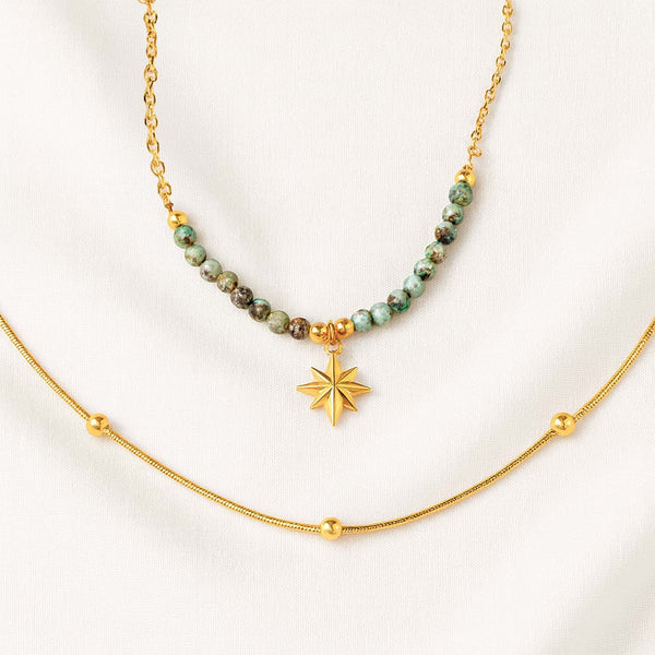 Gold necklace with green beads and a star pendant on a white background
