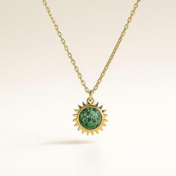 Gold necklace with a green gemstone pendant on a beige background